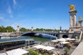 Alexander III bridge and cafe in docks area in a sunny summer day, blue sky in Paris, France Royalty Free Stock Photo