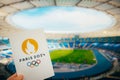 PARIS, FRANCE, JULY 7, 2023: Embracing the Symbol: Athlete Holds Iconic Emblem of Paris 2024 Summer Olympics, with Modern Stadium Royalty Free Stock Photo