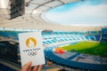 PARIS, FRANCE, JULY 7, 2023: Embracing the Symbol: Athlete Holds Iconic Emblem of Paris 2024 Summer Olympics, with Modern Stadium Royalty Free Stock Photo