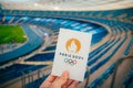 PARIS, FRANCE, JULY 7, 2023: Embracing the Symbol: Athlete Holds Iconic Emblem of Paris 2024 Summer Olympics, with Modern Stadium Royalty Free Stock Photo