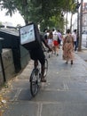 A food-delivery cyclist rides on the sidewalk