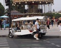 A man stands close to a tuktuk in Paris