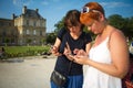 Two girls look at a smartphone at Luxembourg Palace, Jardin du Luxembourg is public park in Paris, garden of the French Senate