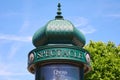 Typical green advertising column or Morris column in Paris in a sunny day, blue sky