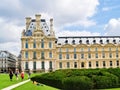 Ornate traditional style building set Paris gardens with people on path and lawn