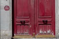 Paris, France - June 26, 2019: Red painted wooden double door with vintage handles. Shabby surface of gate. Scratched wood