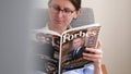 Woman reading newspaper Forbes top billionaires list