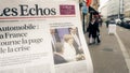 Man reading buying French Les Echos newspaper at press kiosk Street