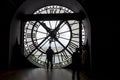 PARIS, FRANCE - MAY 9, 2019: Famous clock with roman numerals and silhouette of man looking into round window in Orsay Museum,
