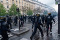French CRS riot police charging violent protesters in a street of Paris, France