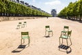 Lawn chairs scattered in a tree lined alley in the Tuileries garden in Paris, France Royalty Free Stock Photo