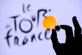 PARIS, FRANCE - MAY 25, 2020: Hands silhouette holds covid 19 virus, logo of cycling race Tour de France in background