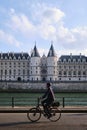 Paris, France, A man riding a bicycle on banks of seine river in front of La Conciergerie, former prison transformed into courts