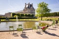 A man sunbathing on a metal lawn chair by a basin in the Tuileries garden in Paris with the Louvre palace in the background Royalty Free Stock Photo