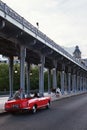 Paris, France, A red clasical sport car with long steel columns of Passy Viaduct located at Pont de Bir Hakeim Bridge