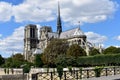 Paris, France. Notre Dame Cathedral from bridge over Seine river. Trees and river walk. Blue sky with clouds. Royalty Free Stock Photo