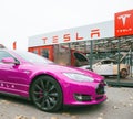 New fuchsia colored Tesla Motors Model S car parked near a glass modern