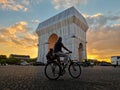 Male with his dog cycling near the Arch of Triumph in Paris at sunset