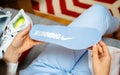 Overhead view of woman hand holding new running Nike shoe sole in blue color