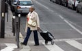 Reputable elderly Asian Woman with trolley crossing street