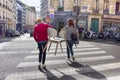 Two girls carry chairs through the crosswalk