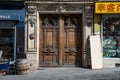 Paris / France - 06 26 2019: Street of European city with shop windows and antique door. Vintage wooden doorway with