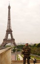 PARIS-MAY 24, 2015: Behind French soldier in uniform standing at palace Trocadero looking at the Eiffel Tower in clouded day.