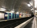 Paris metro station with a gray apron and a black tunnel, the path goes into the distance, decorated with white tiles