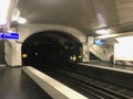 Paris metro station with a gray apron and a black tunnel, the path goes into the distance, decorated with white tiles