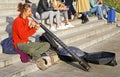 Closeup of street musician sitting on steps playing didgeridoo