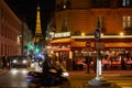 Eiffel tower illuminated at night and street with people and typical restaurant in Paris, France Royalty Free Stock Photo