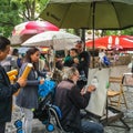 Paris street artist sketches baby, who wiggles in father`s arms, on Place du Tertre, Montmartre