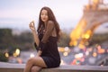 Paris woman smiling eating the french pastry macaron in Paris against Eiffel tower.