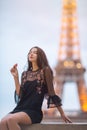 Paris woman smiling eating the french pastry macaron in Paris against Eiffel tower.