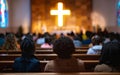 Parishioners sit reverently in a church, their attention directed towards a brightly lit cross. The atmosphere is one of