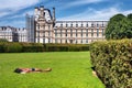 The Parisian citylandscape - relaxing young man takes sunbathing on the lawn the Tuileries Garden beside Louvre Palace