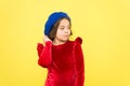 Parisian kid in french beret hat and elegant red dress on yellow background, retro fashion