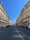 Parisian street with beautiful buildings with the July Column in the background under a blue sky