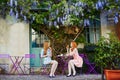 Parisian women drinking coffee together in an outdoor cafe with wisteria in full bloom