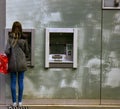 Parisian young woman makes monetary transaction in street ATM