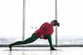 Parivritta parsvakonasana. Beautiful yoga woman practice twist poses in a big window hall