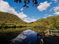 Beautiful morning view of a creek with reflections of deep blue sky, light clouds, mountains and trees Royalty Free Stock Photo