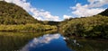 Beautiful morning view of a creek with reflections of deep blue sky, light clouds, mountains and trees Royalty Free Stock Photo