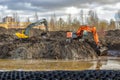 Two powerful excavators dig a pond in the park