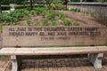 A park bench with an engraved quote by Edmund Spenser on a brick pathway in a flower garden Royalty Free Stock Photo