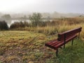 Park bench by a foggy pond