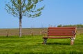 Park Bench on grass with field behind it scenic