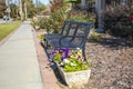 A park bench next to a side walk with colorful flowers Royalty Free Stock Photo