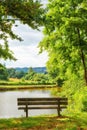 Park bench overlooking the view by the lake in the countryside. Scenic view of trees and greenery by a river with an Royalty Free Stock Photo