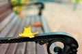 A park bench on which lies a yellow and red maple leaf. Autumn yellowed sheet ice on a wooden bench. Close up macro Royalty Free Stock Photo